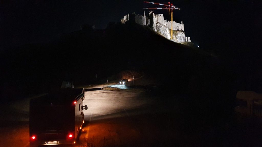 Karavan pod vysvieteným hradnom v noci